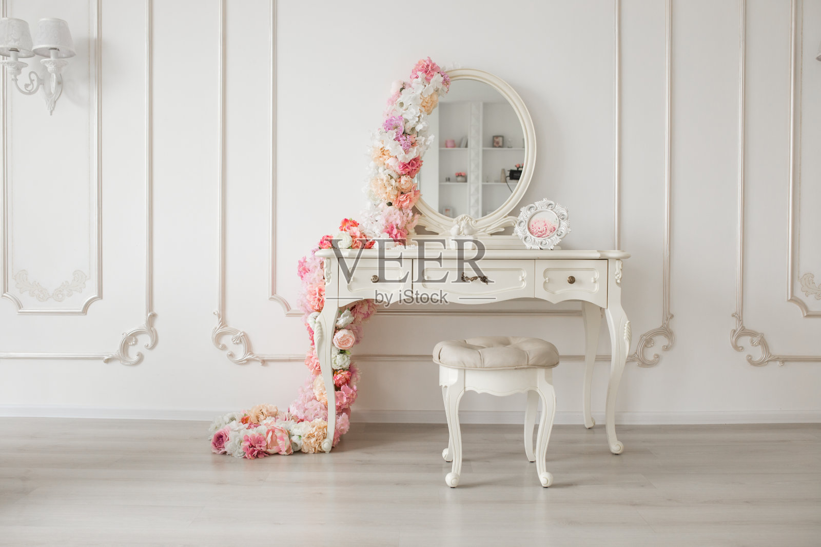 复古风格的闺房桌子与圆镜和鲜花。白色明亮的房间照片摄影图片