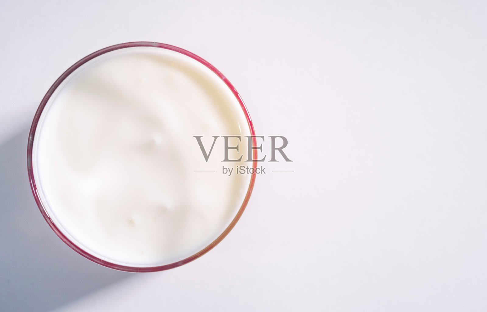 宏观计划有机纯无麸质乳制品。光滑的酸奶表面在透明的玻璃玻璃上特写，白色的背景，孤立照片摄影图片