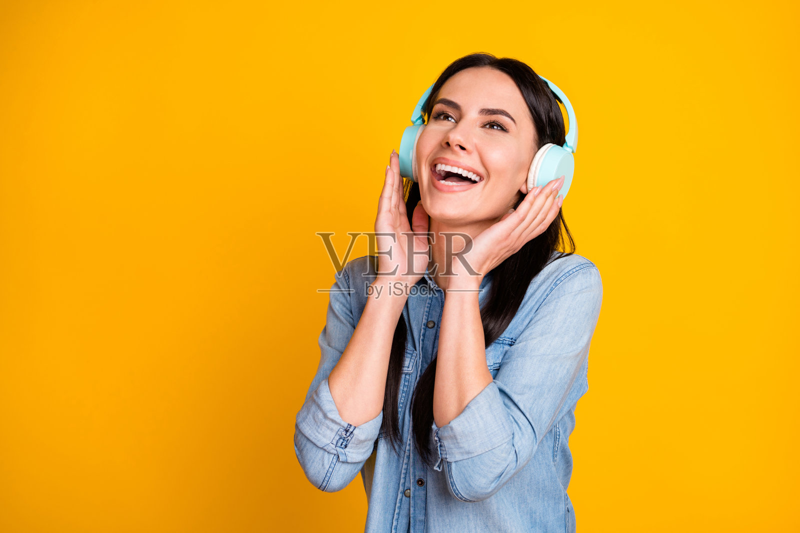 她的特写肖像，她好看的，有吸引力的，相当愉快的，愉快的，深肤色的女孩听灵魂爵士单表收音机上明亮生动的闪耀，明亮的黄色背景照片摄影图片