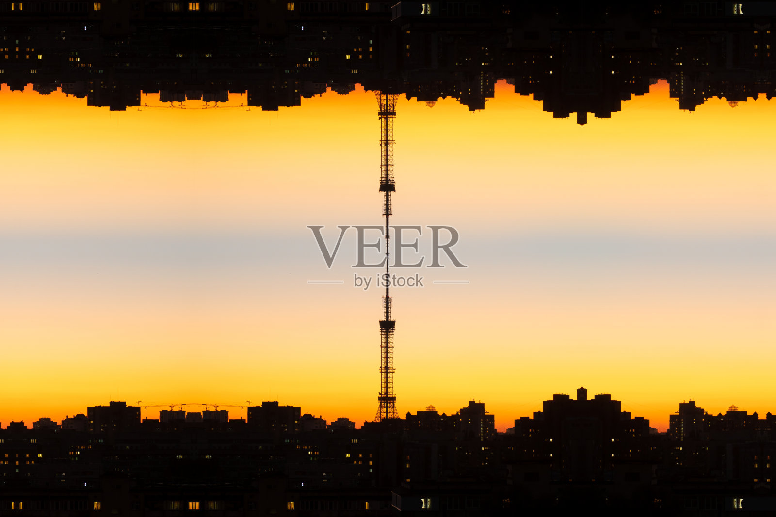 夕阳下颠倒的橙色城市景观，垂直反射，在中心有一个塔连接两个城市景观。反映的城市景观，看起来就像音轨的声像图。照片摄影图片