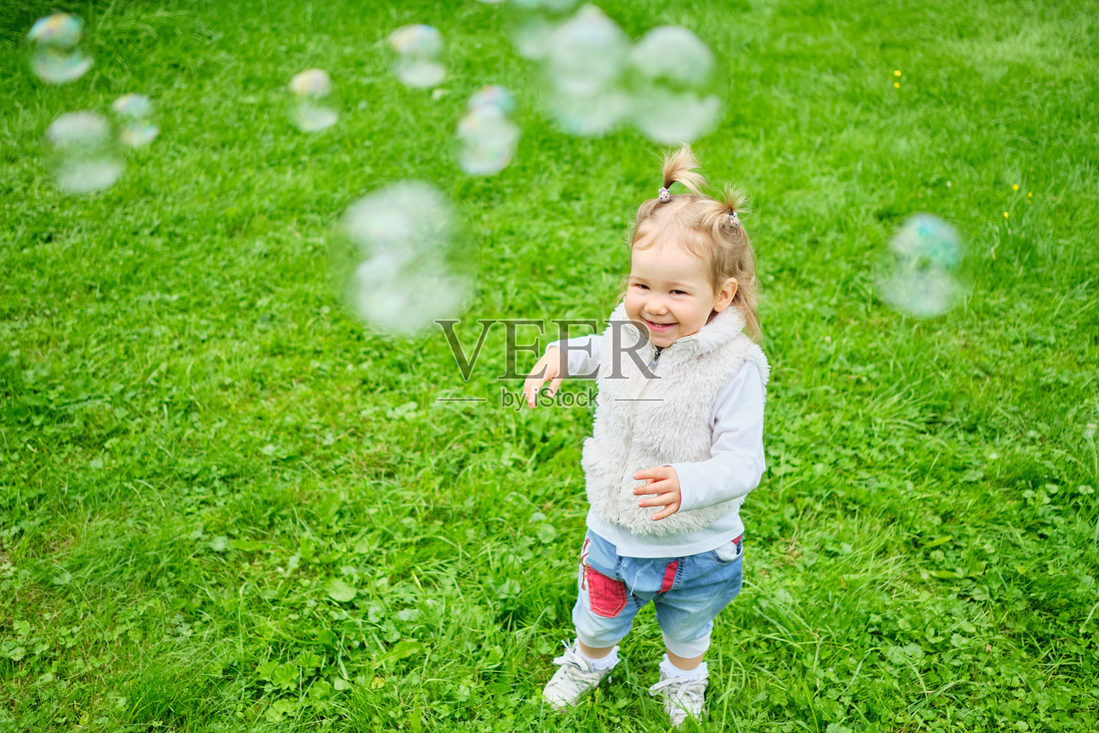 快乐的幼童在夏季公园追逐肥皂泡。照片摄影图片