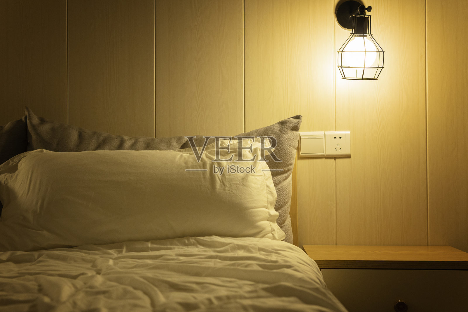 在柔和的灯光下，一个舒适的房间，一个舒适的床和床头柜照片摄影图片