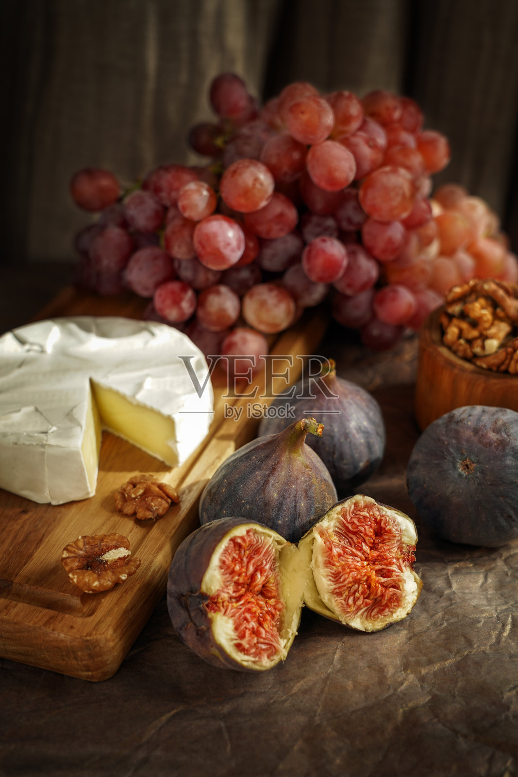 有无花果、法国布里干酪、粉红葡萄和核桃的秋季静物画。光线模式甚至强调了最小的细节。食品的海报。照片摄影图片