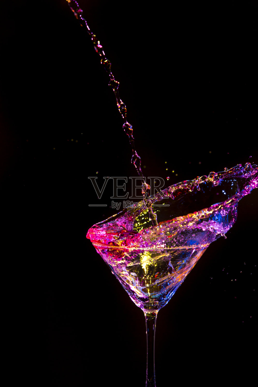 摄影。葡萄酒杯中彩色液体的喷出。孤立的黑色。垂直的图像组成照片摄影图片