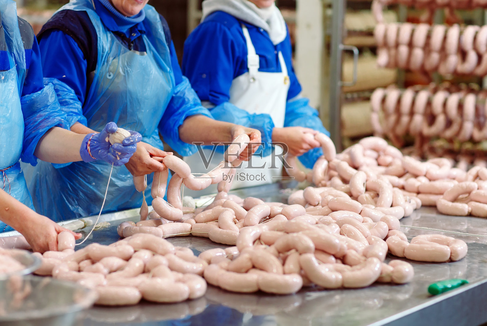 在肉工厂加工香肠的屠夫。照片摄影图片