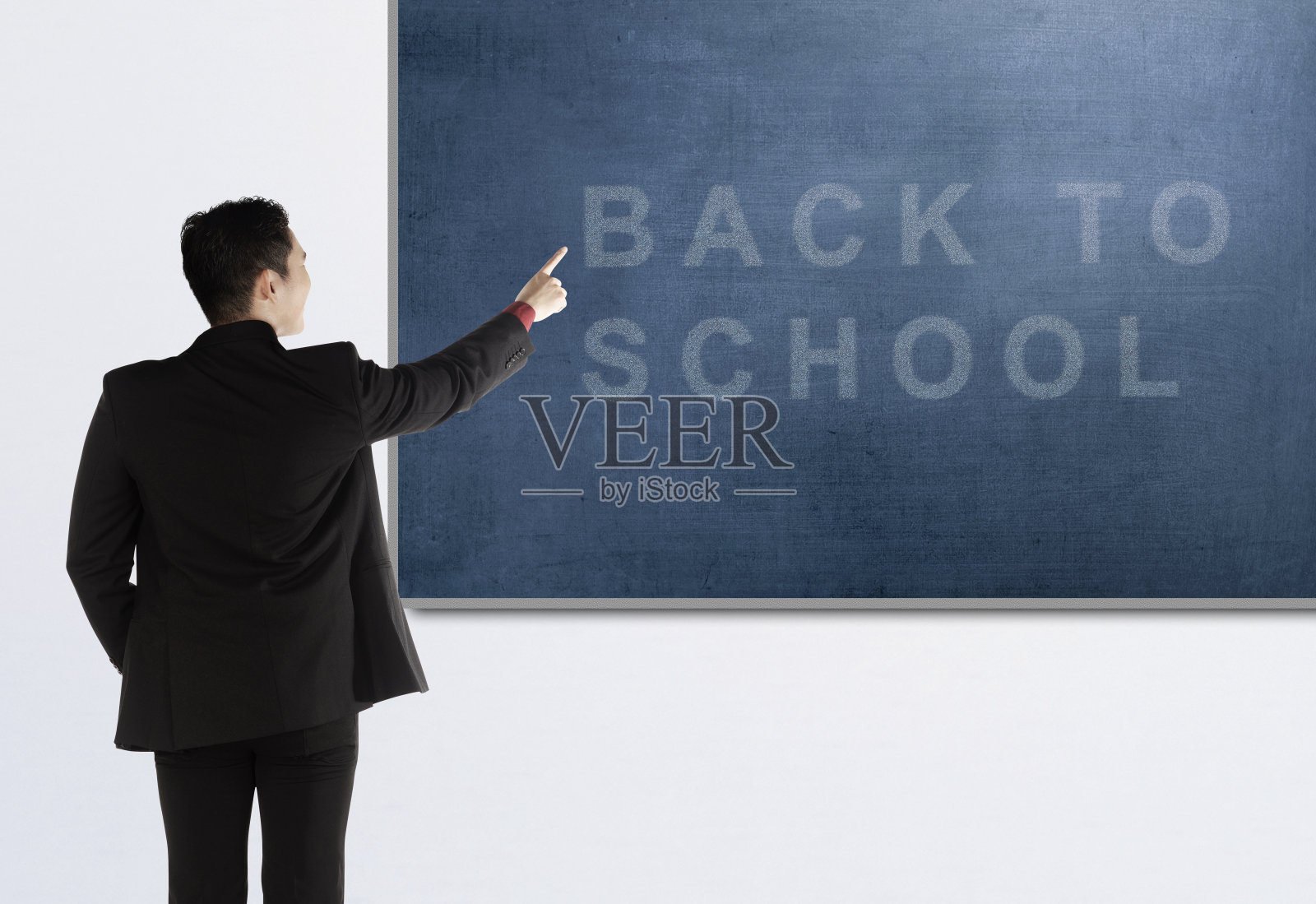 背面的亚洲教师男人指向黑板与回到学校的文本照片摄影图片