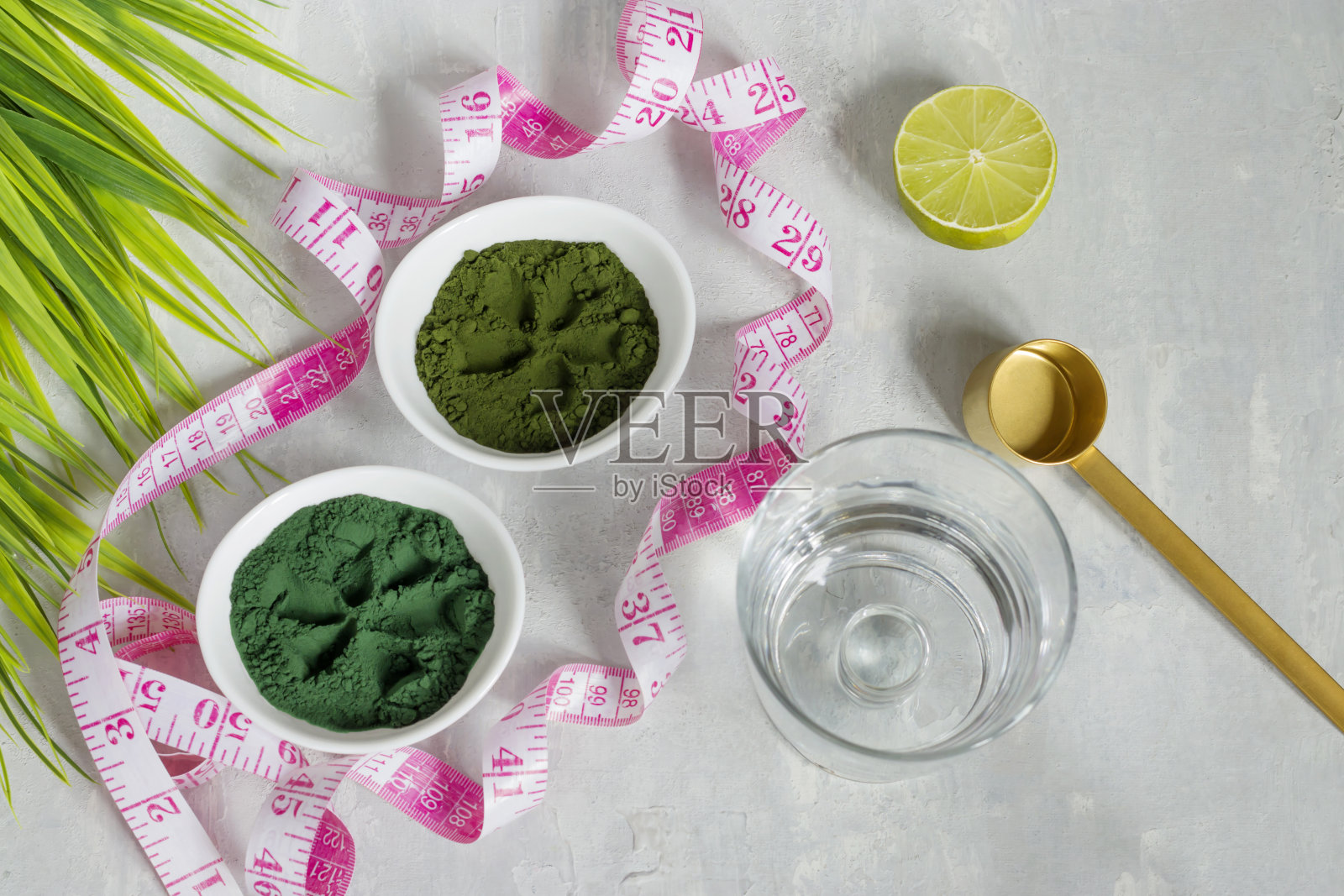 小球藻和螺旋藻粉在光线背景下。绿色超级食物为素食者排毒。健康的生活方式的概念。测量数字的卷尺照片摄影图片