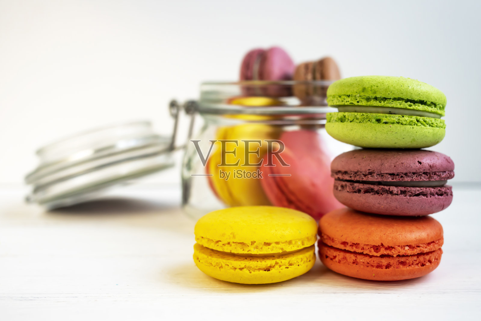 彩色的马卡龙在一个罐子里，在一个蓝色的木制背景。照片摄影图片