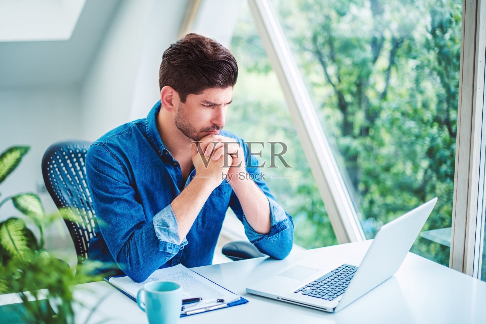 在笔记本电脑上工作的商人看上去若有所思照片摄影图片