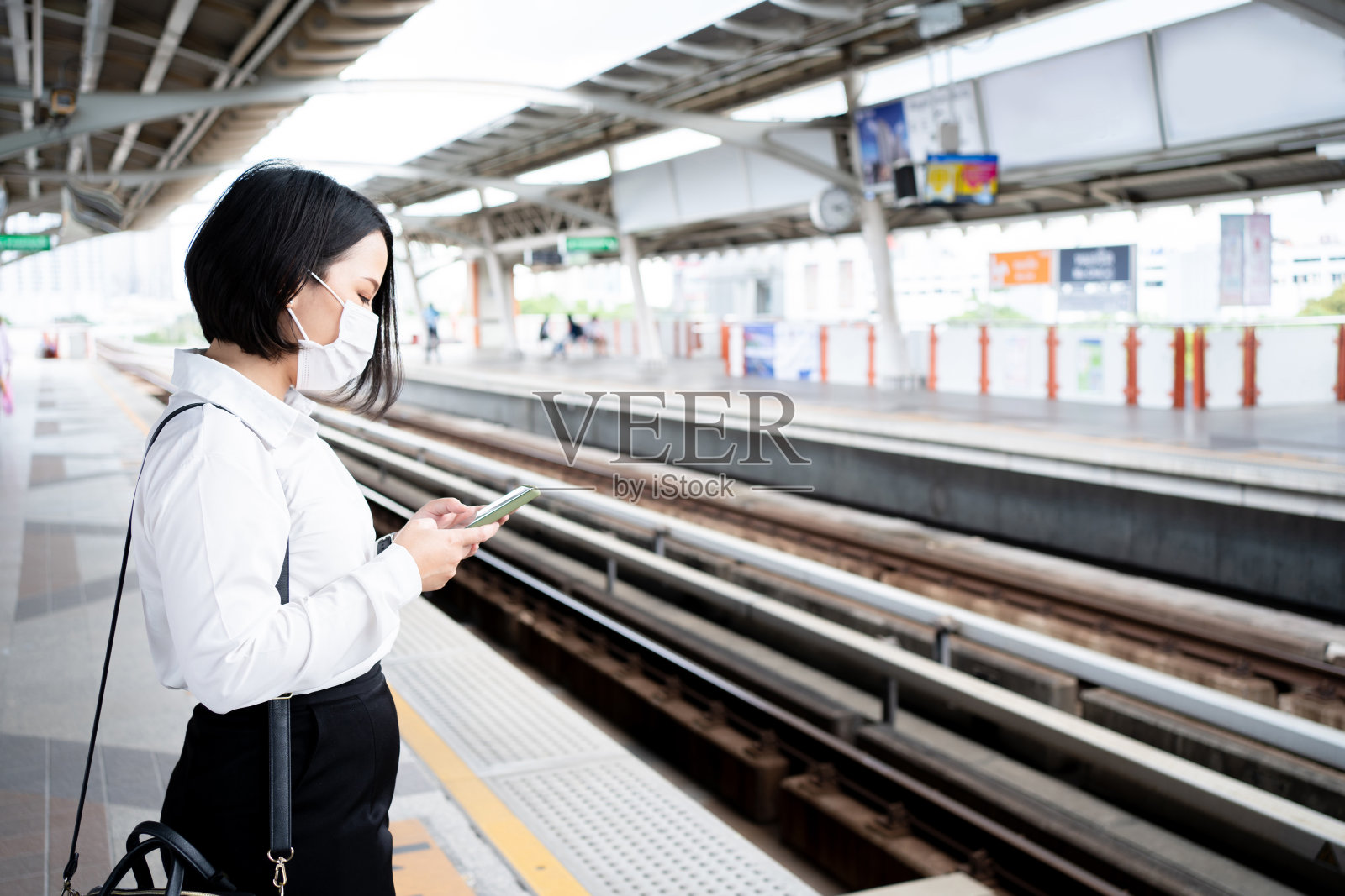 一名亚洲女子在等地铁时使用智能手机的特写照片。照片摄影图片