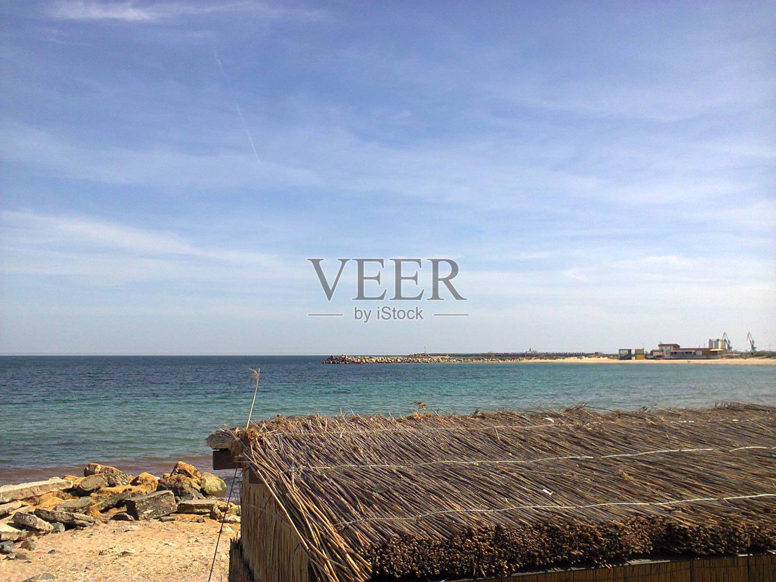 夏天晴朗的蓝天透明的翠绿色岩石海岸茅草棚照片摄影图片