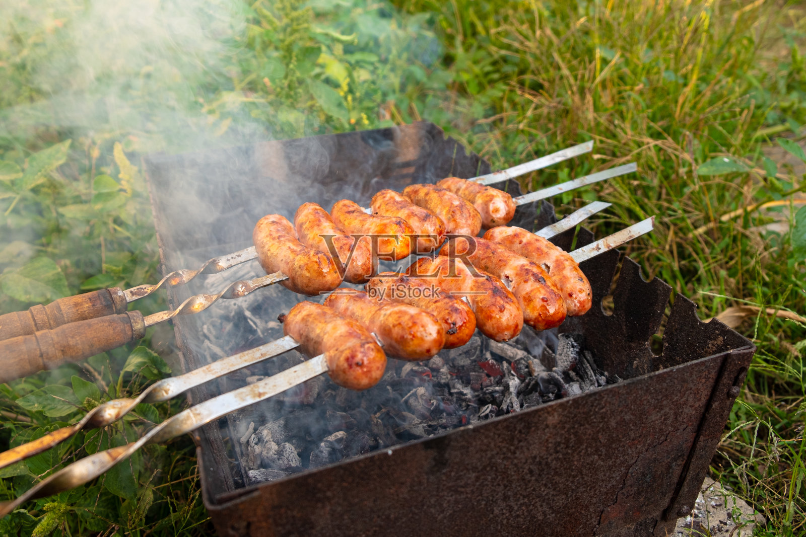 夏日野餐，户外烹饪的食物，烤猪肉香肠串在烟熏烤皮上照片摄影图片
