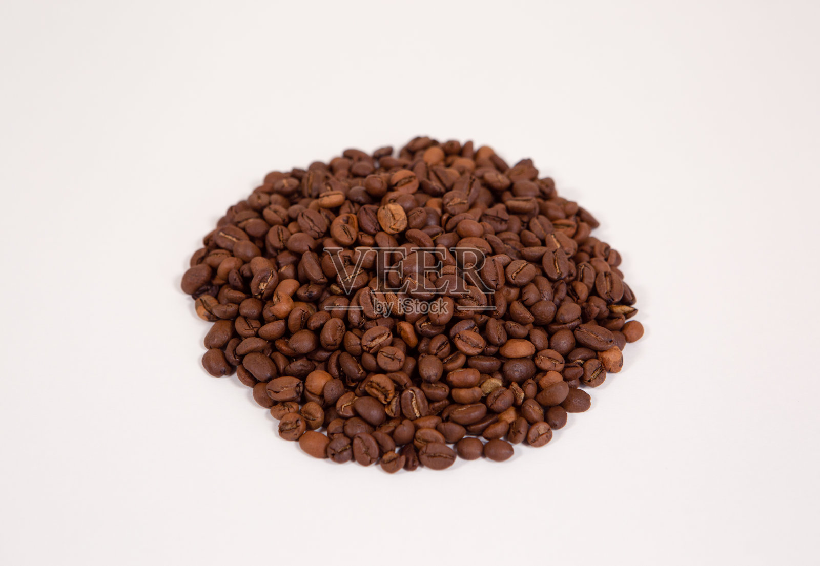 在一个白色的背景上，在一个均匀的堆孤立烤咖啡豆。照片摄影图片