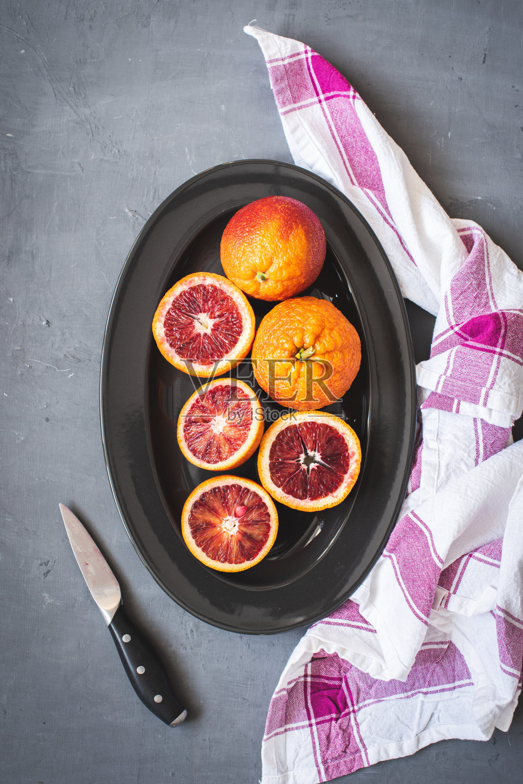 鲜红的橙子放在黑色盘子上，背景是深灰色照片摄影图片