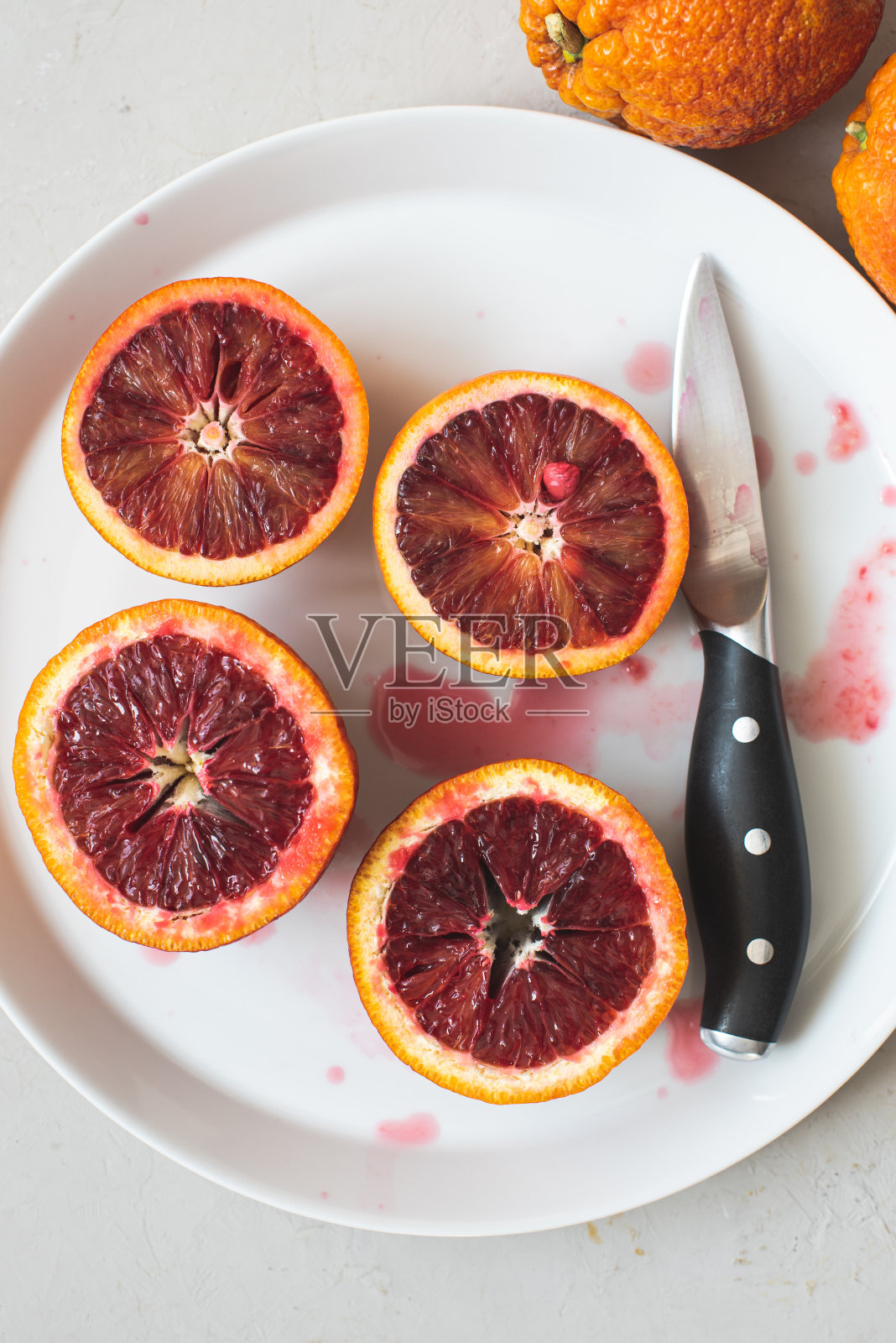 雪白的盘子和一把刀上放着新鲜的血橙照片摄影图片