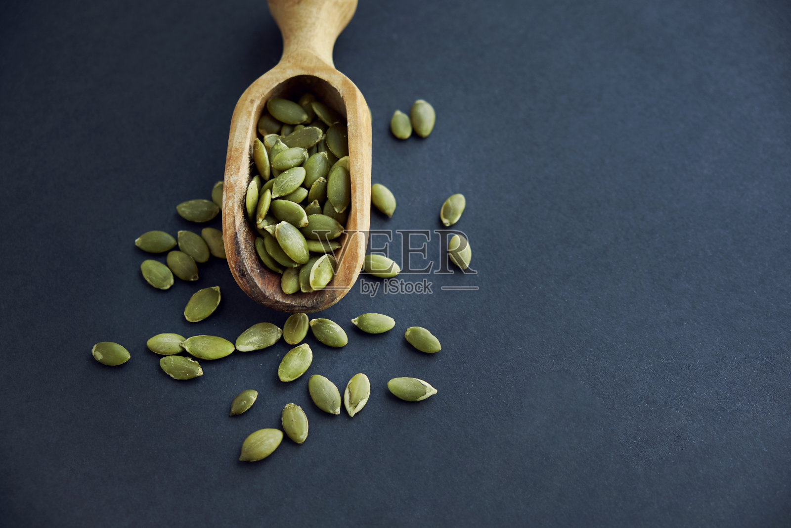 木碗里装着南瓜籽，还有老式的勺子。靠近一个黑色的背景。文本复制空间照片摄影图片