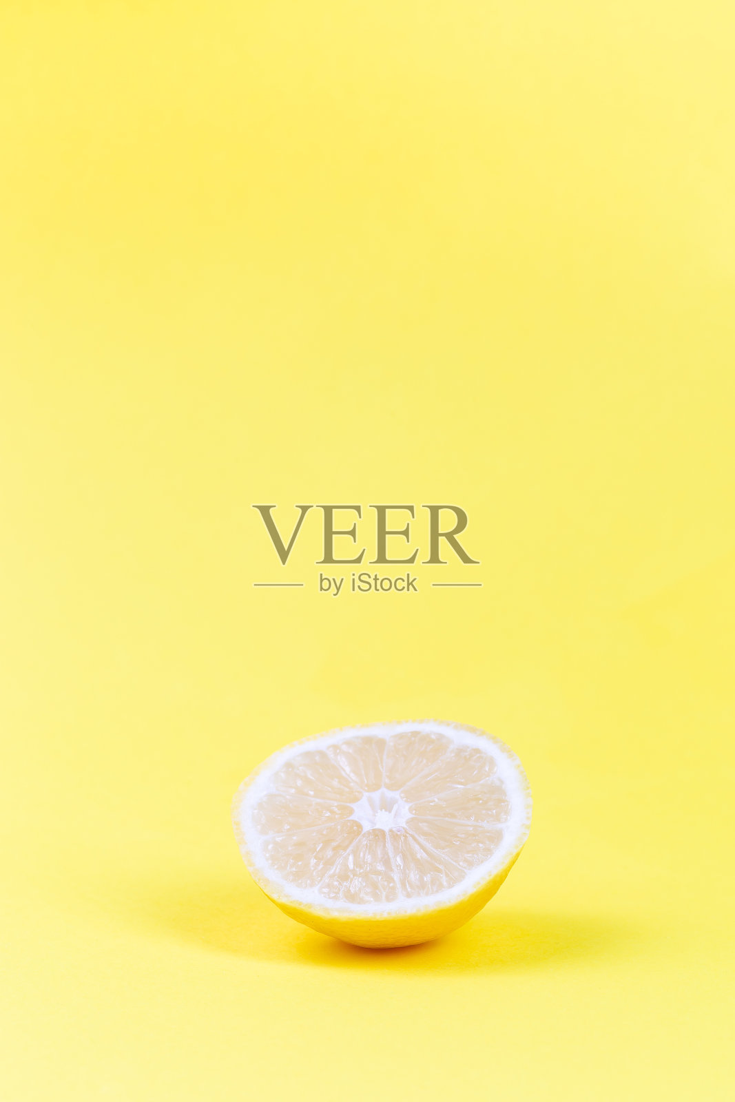 黄色背景上的一片柠檬，垂直，复制空间照片摄影图片