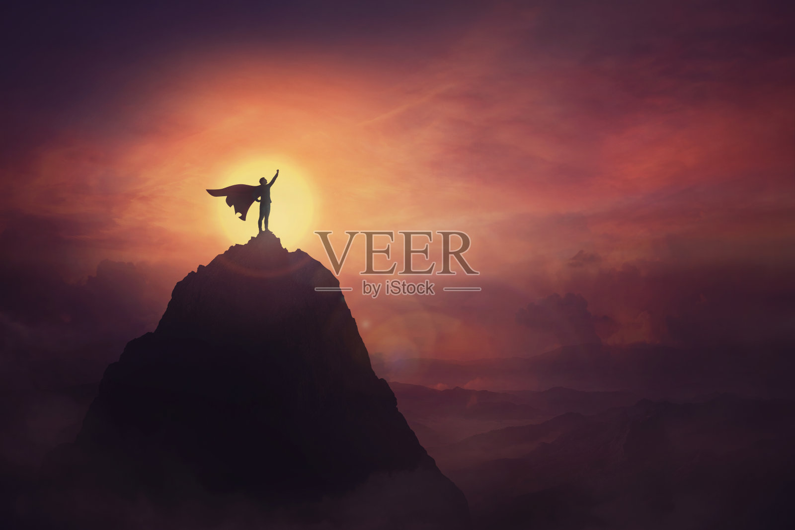 概念上的日落场景，超级英雄勇敢地站在山顶，在地平线上举起一只手，作为一个胜利的领导者。英雄的力量和动力，克服障碍。照片摄影图片