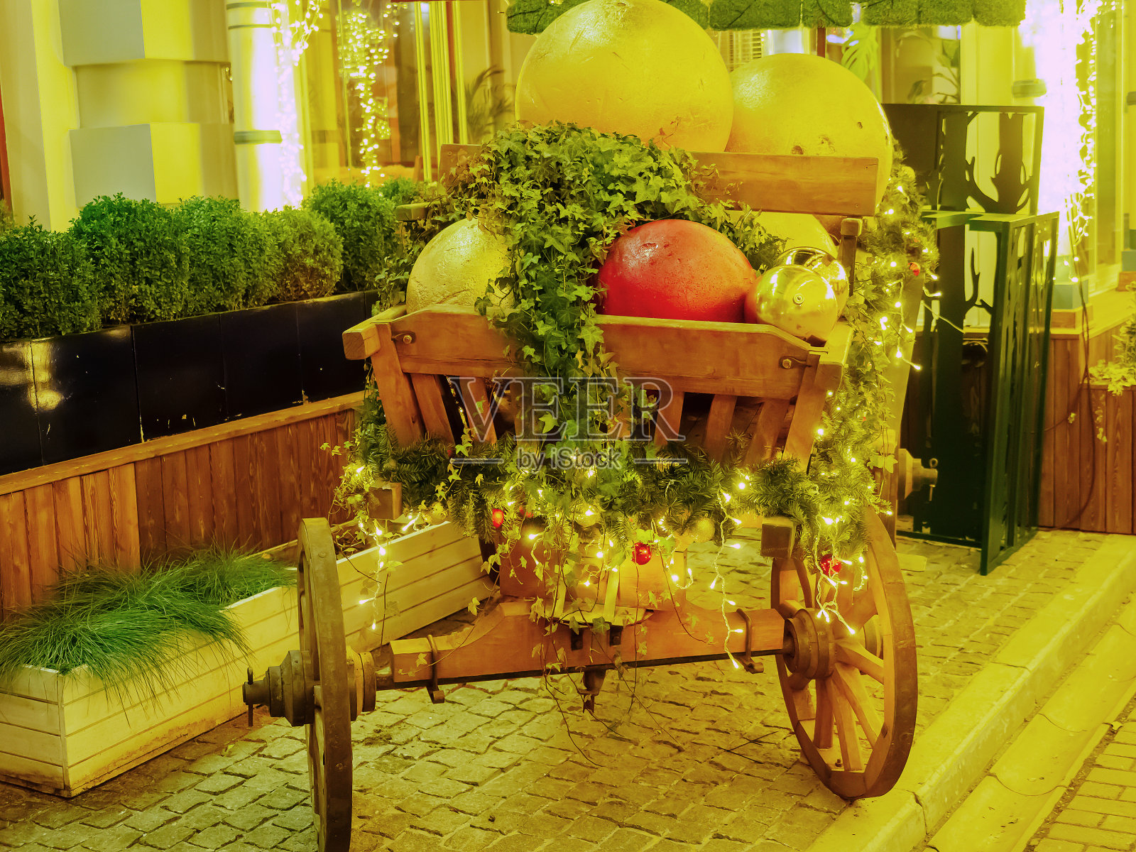 挂着巨大圣诞球和常青藤的木车停在铺着花环的石板上照片摄影图片
