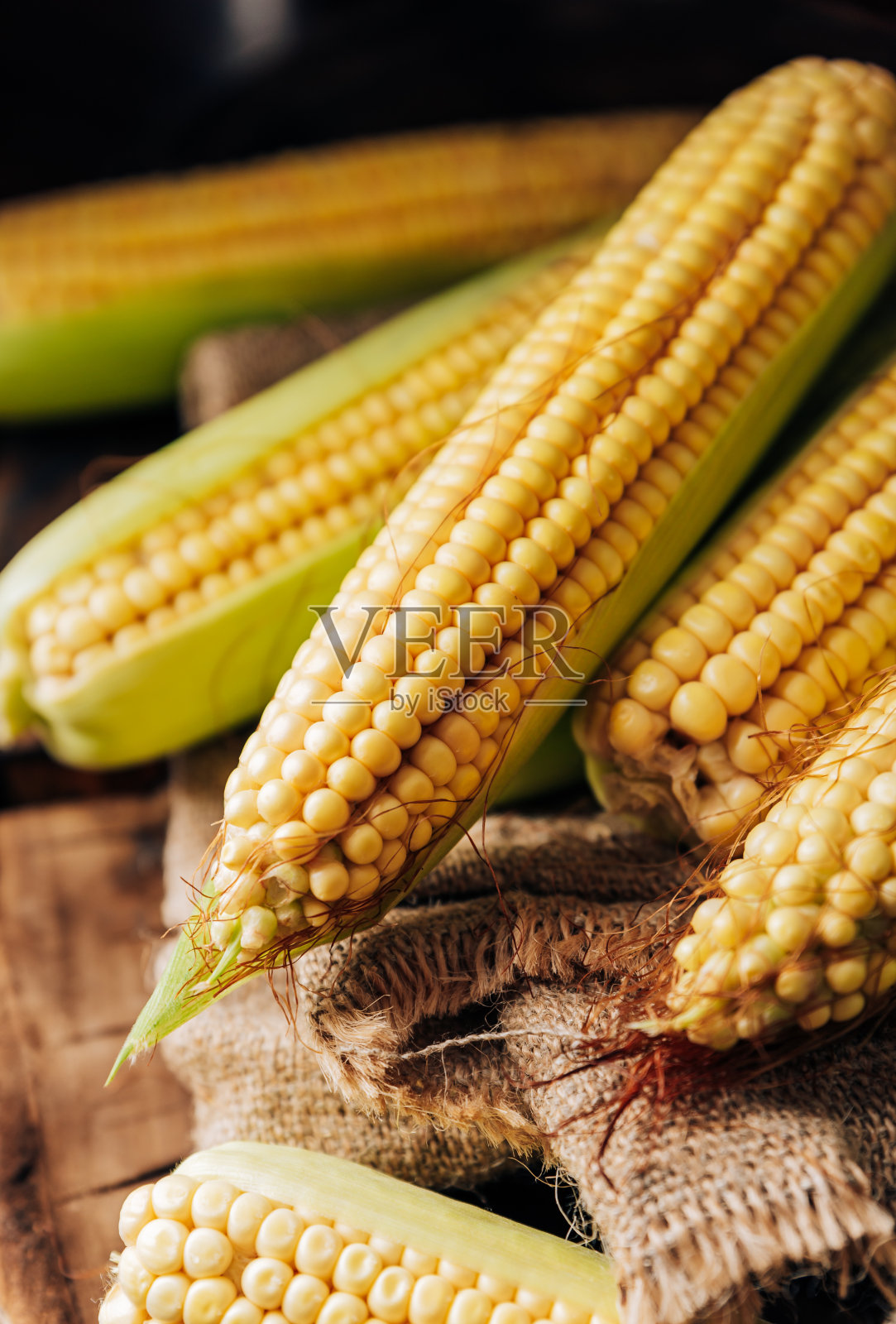 棕色天然木纹背景上的新鲜玉米棒，特写照片摄影图片