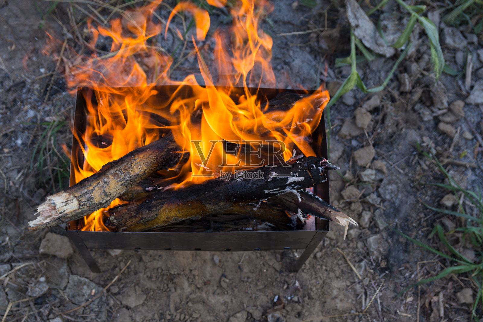 柴火在烤架上烧成煤。用炭火煮肉。日落时在营地吃晚餐照片摄影图片