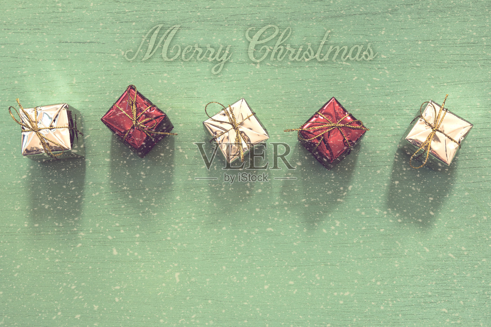 圣诞快乐文字和礼盒装饰在木桌的背景上照片摄影图片