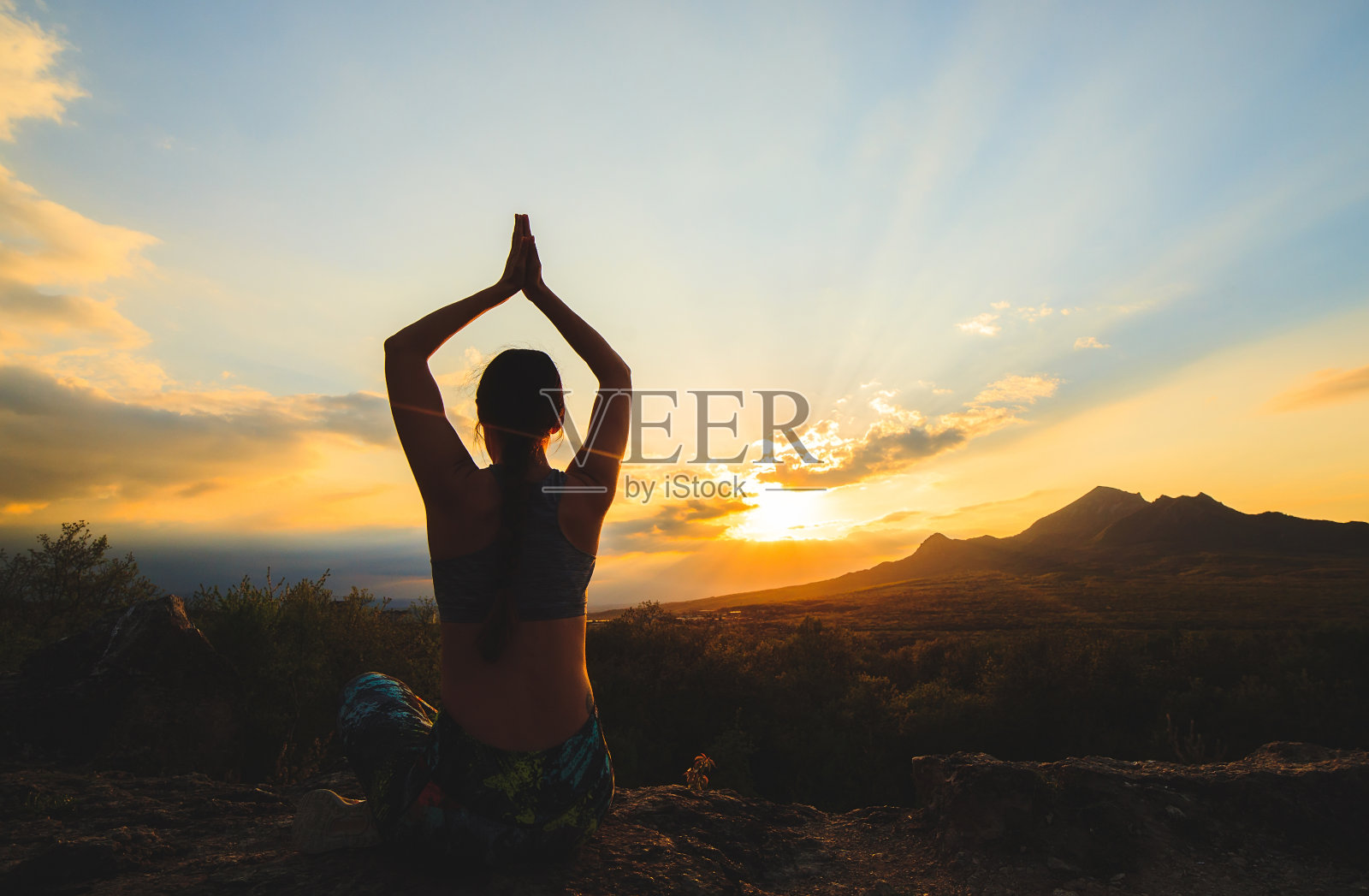 年轻女子在日落或日出时在美丽的山区练习瑜伽或普拉提。照片摄影图片
