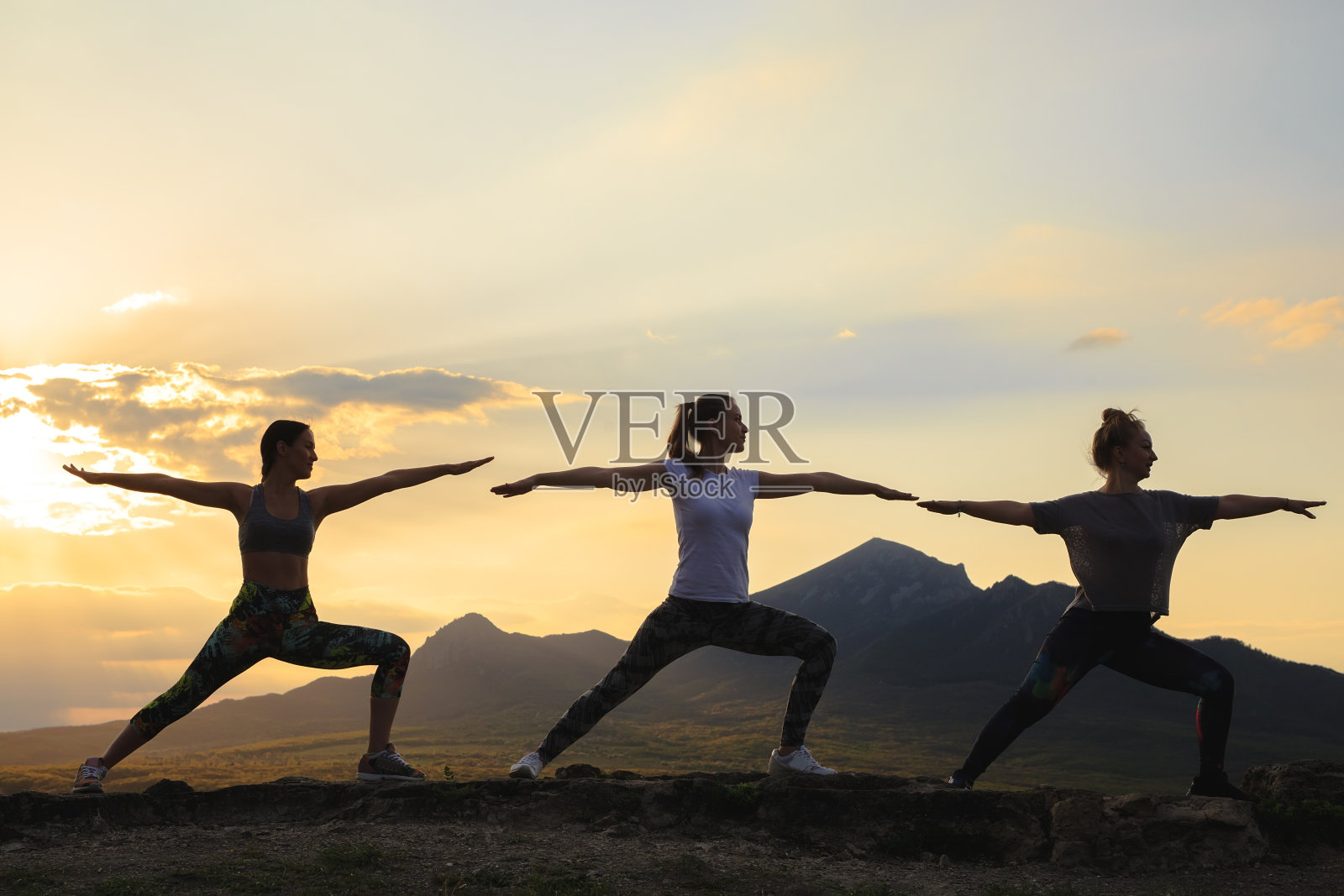 在美丽的山区，日落或日出时，年轻女子练习瑜伽或普拉提的剪影。照片摄影图片