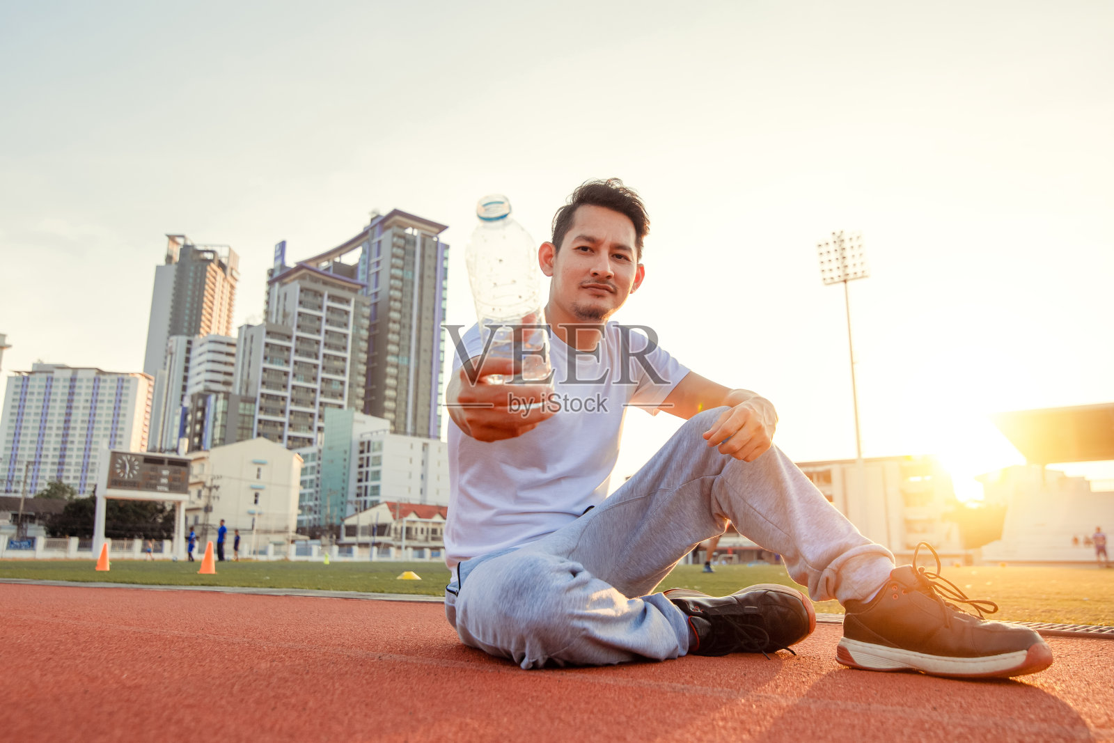 白种人显示水运动后。运动员坐在田径比赛在体育场和日落。照片摄影图片