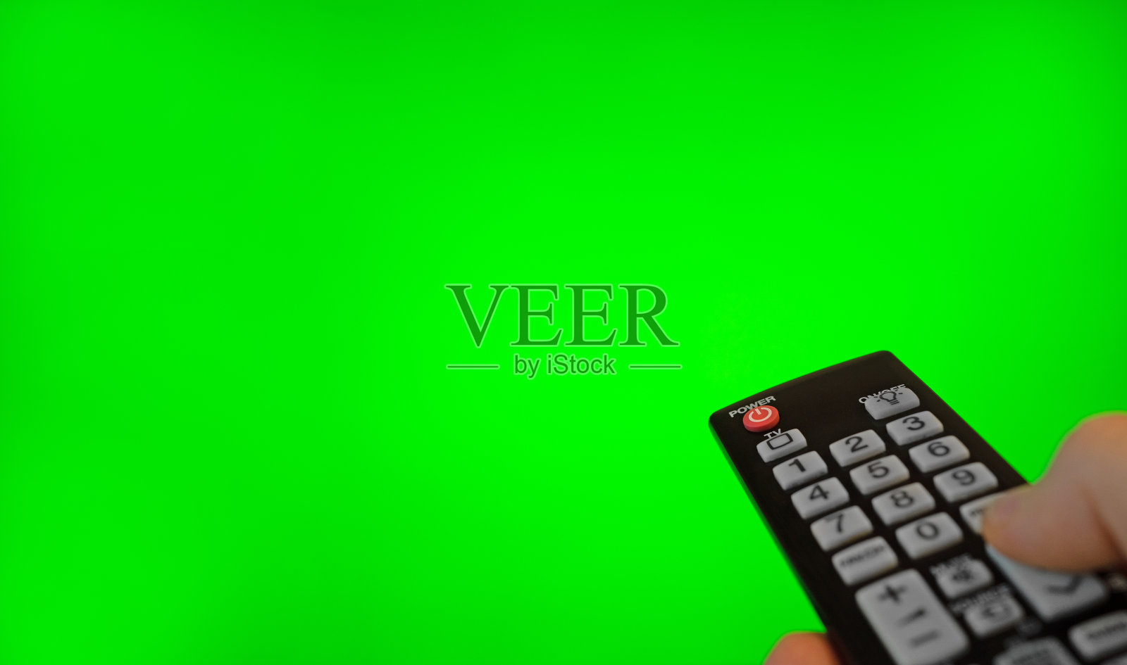 男性用遥控器指着电视屏幕。绿色色度键。照片摄影图片