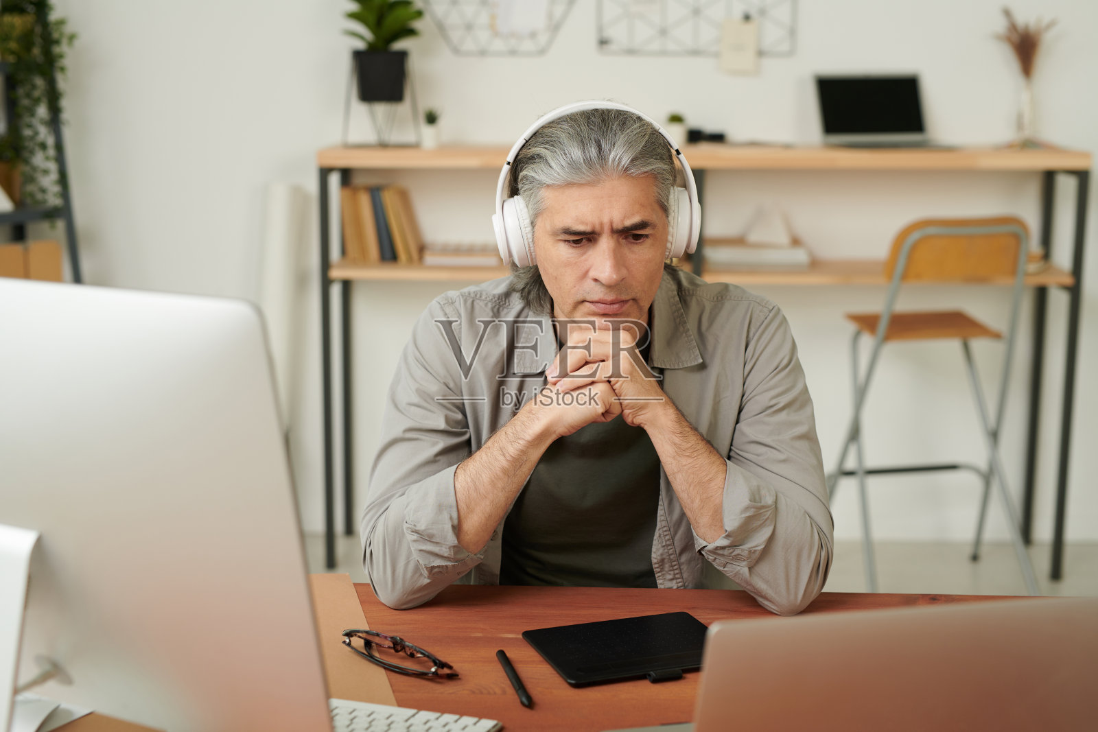 深思熟虑的成熟设计师戴着耳机使用笔记本电脑，同时在互联网上观看有关设计的教育视频照片摄影图片