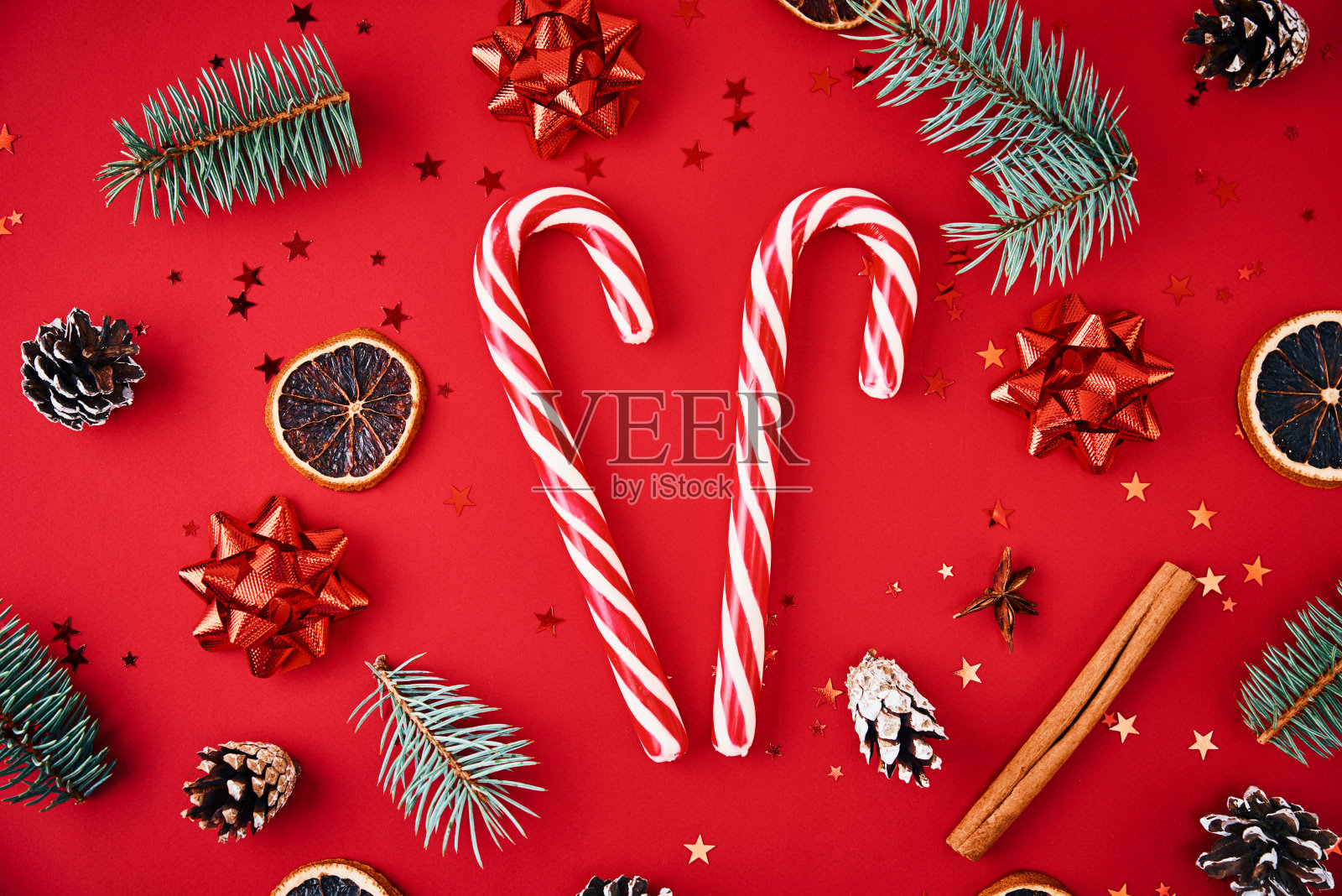 以糖果、冷杉树枝、五彩纸屑和干果为红色背景的圣诞装饰。圣诞作文，俯视图照片摄影图片