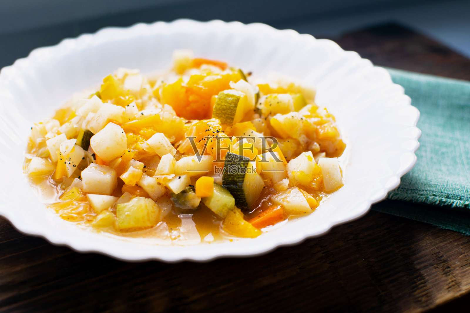 咖啡馆里的白盘子里放着炖蔬菜。烹饪的素食或素食食物。照片摄影图片