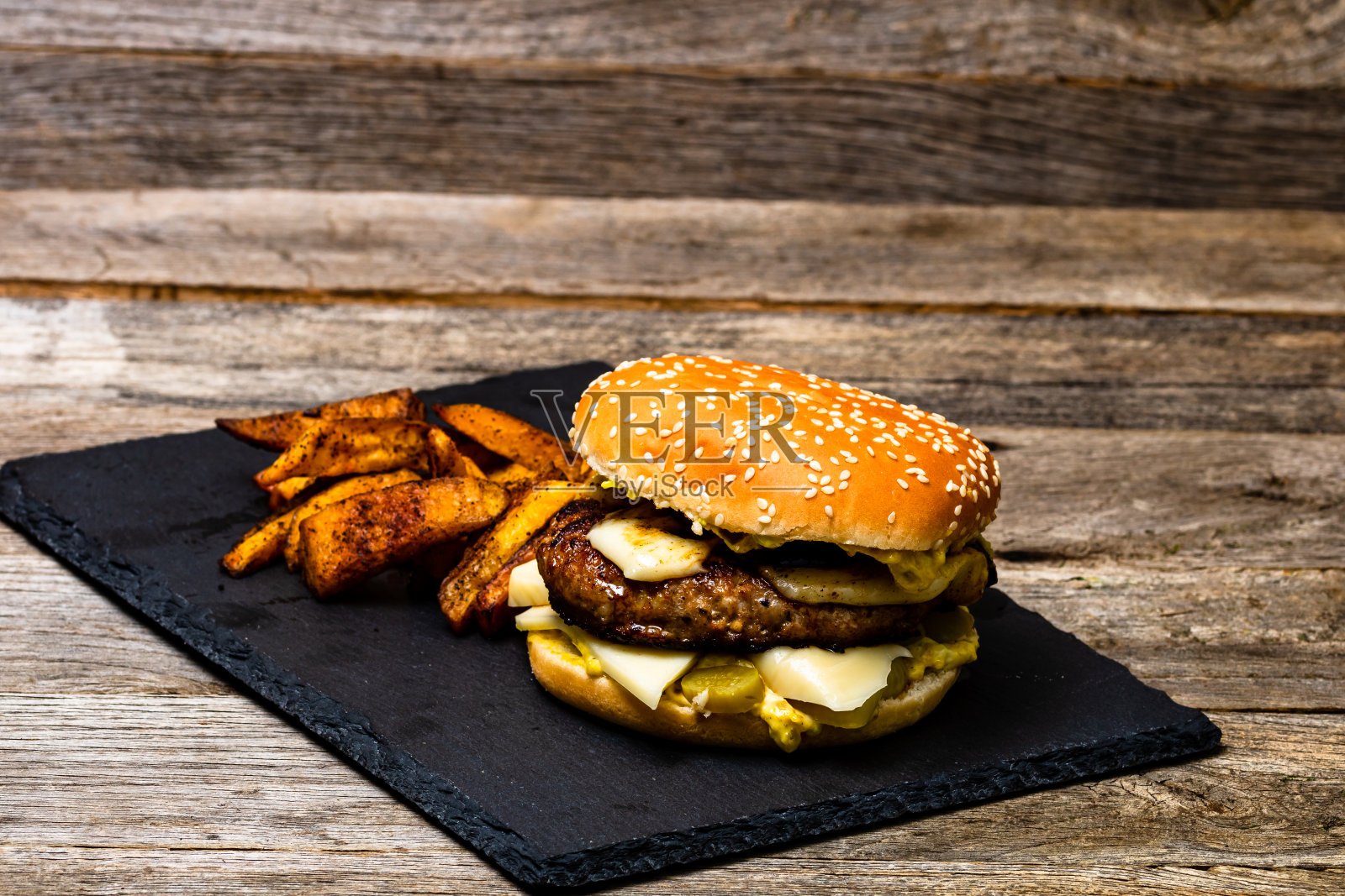 木桌上放着自制的新鲜美味的芝士汉堡和炸土豆照片摄影图片