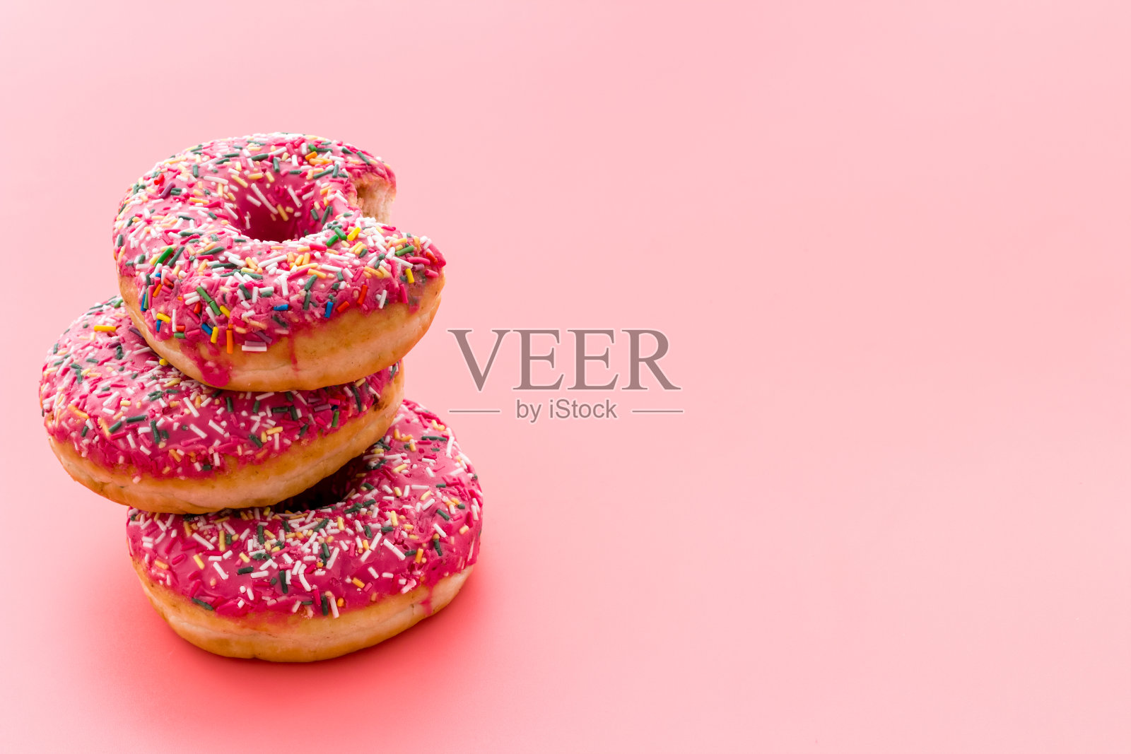 粉红色的浆果甜甜圈接近了。上釉和洒粉烘焙照片摄影图片