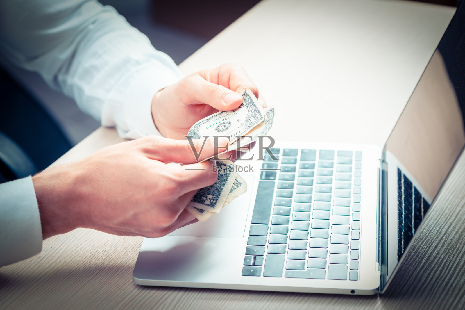 男人手里拿着钞票放在木桌上。商业投资的概念照片摄影图片