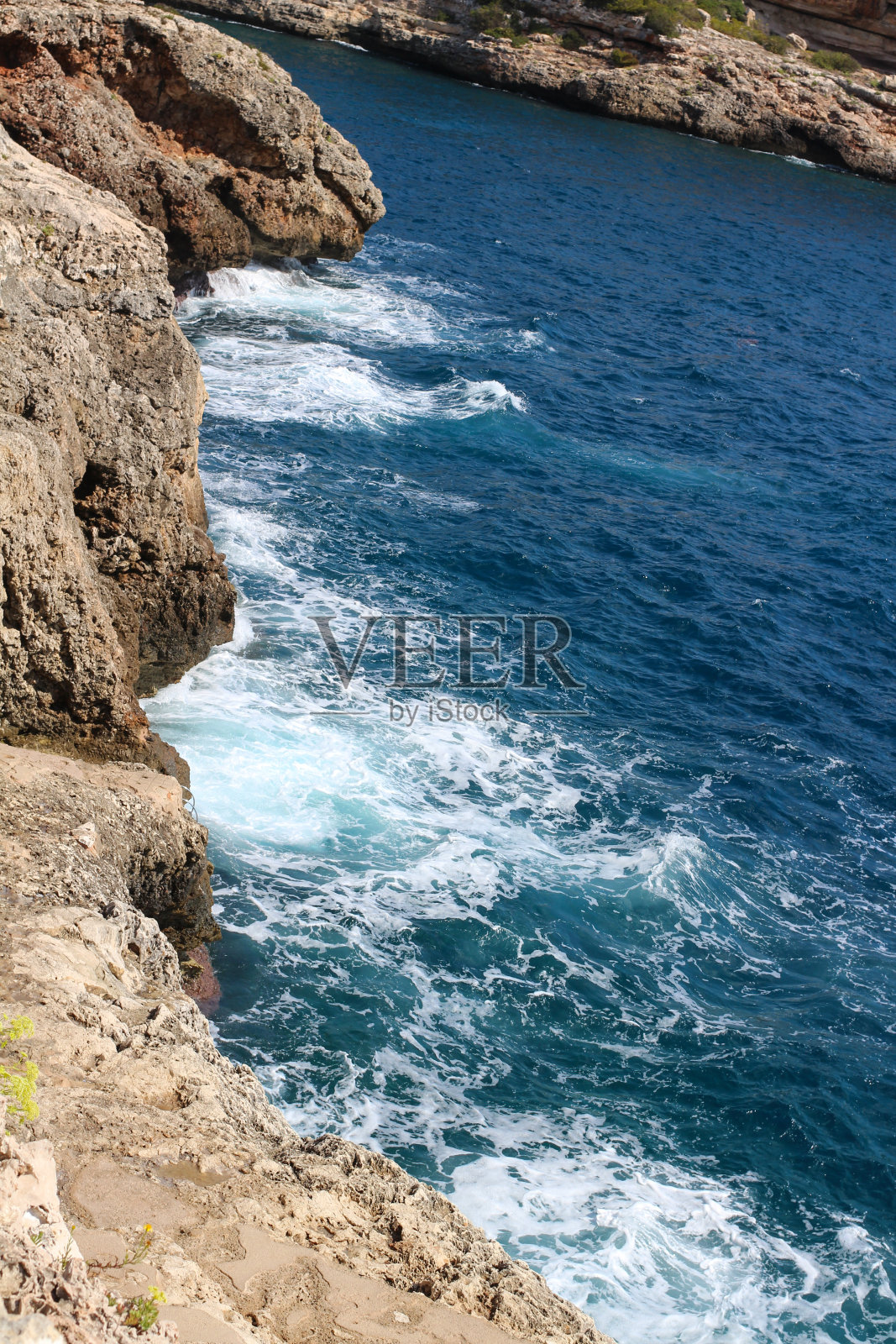 俯瞰石滩和海浪拍打它。马略卡岛。照片摄影图片