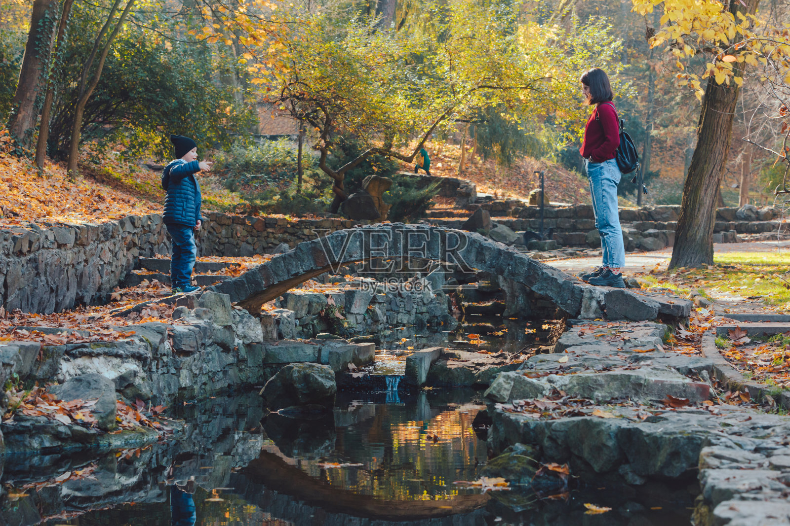 母亲和孩子在秋天的公园散步照片摄影图片