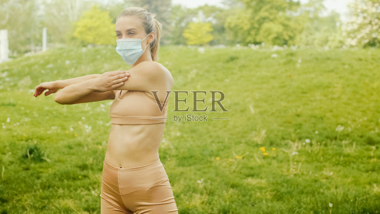 年轻女子戴着抗菌口罩在城市公园做运动。照片摄影图片