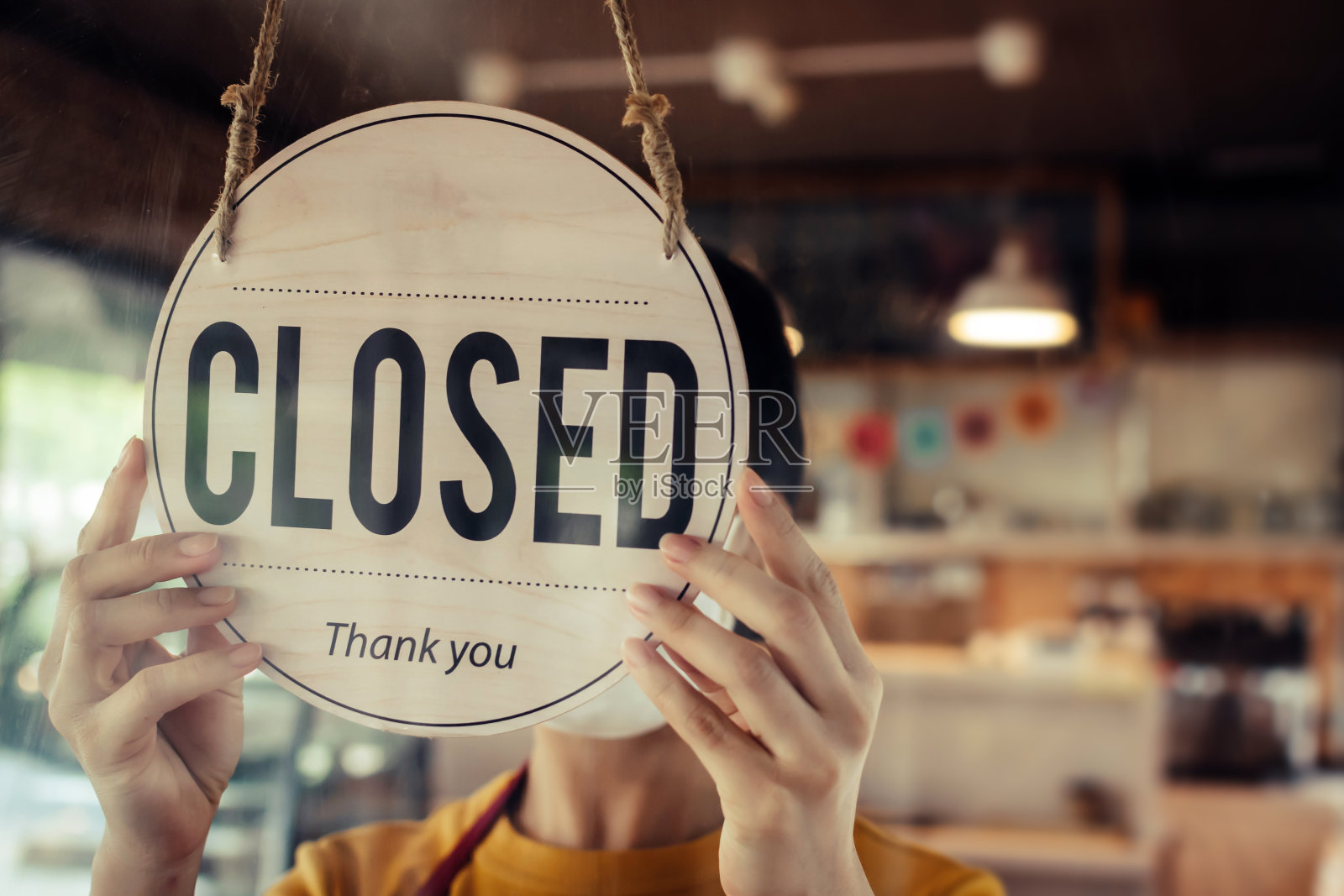 咖啡师，女服务员戴着保护面罩，在现代咖啡馆咖啡馆，咖啡馆餐厅，零售商店，小企业主，食品和饮料概念的玻璃门关闭标志照片摄影图片