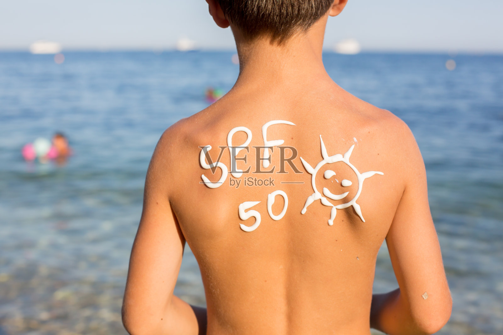 在海滩上，一个背着防晒霜的十几岁男孩照片摄影图片