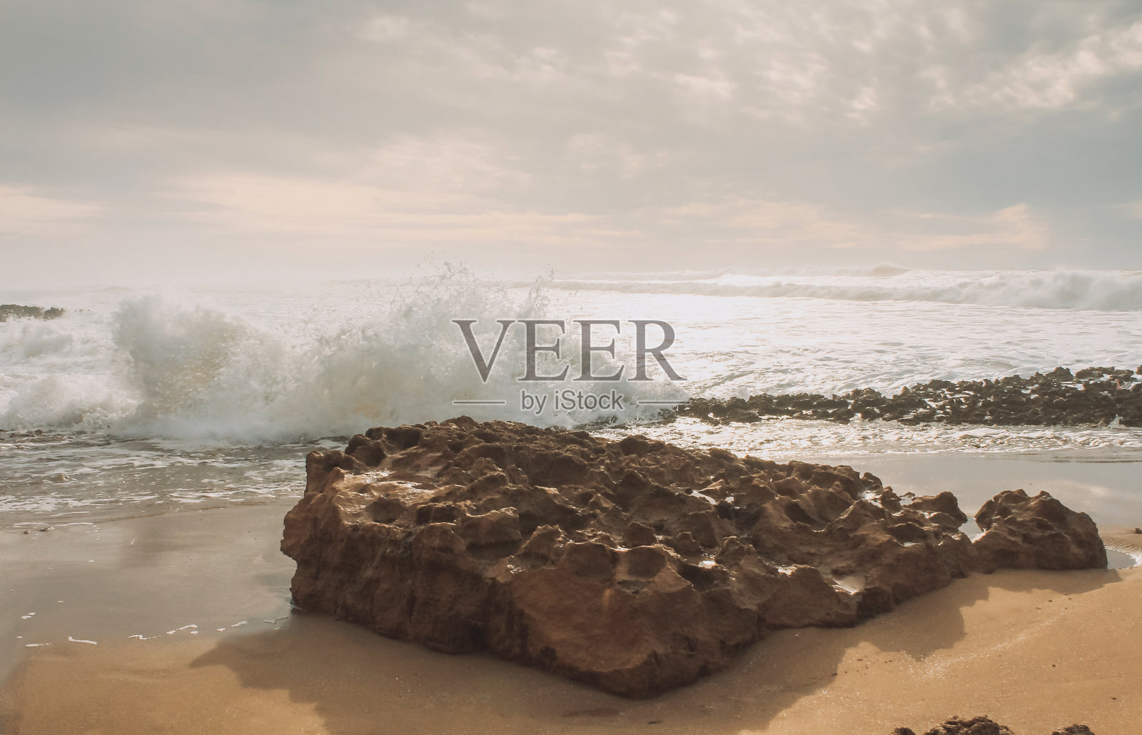 俯瞰大西洋的沙滩，海浪撞击岩石，使溅起的水和白色的空气泡沫泡沫在日落。照片摄影图片