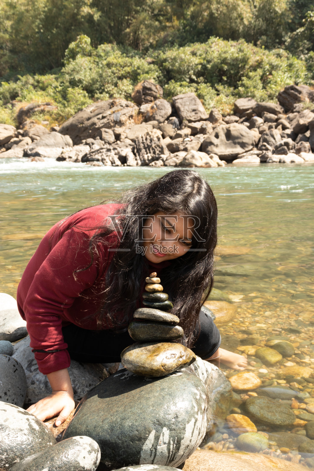 女孩在河边用鹅卵石或石头做金字塔照片摄影图片