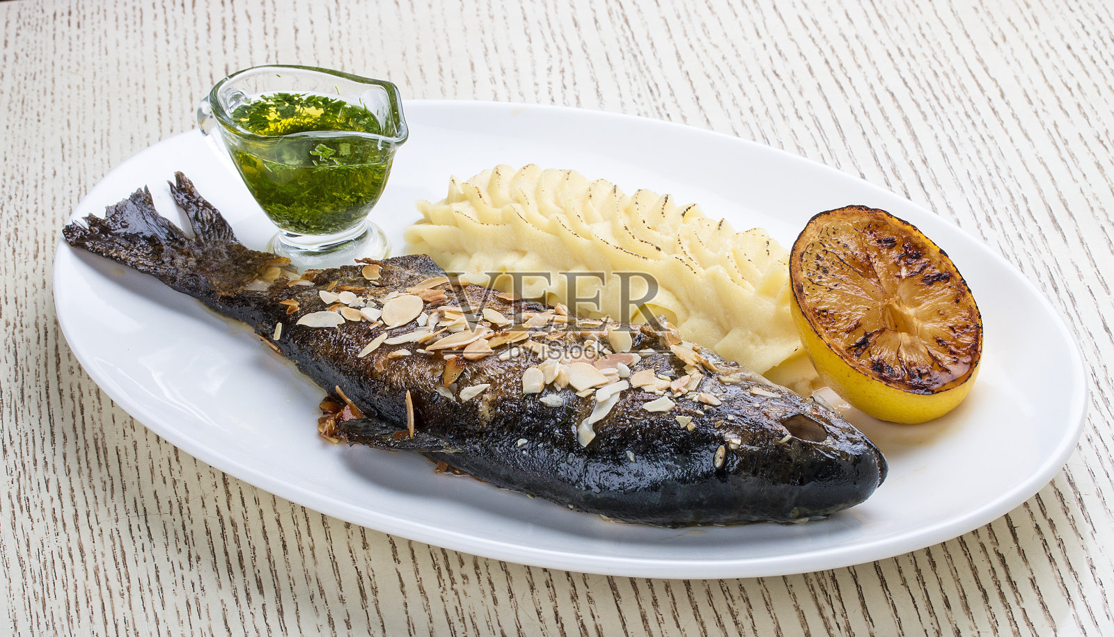 烤鳟鱼配杏仁和土豆泥。在白色背景照片摄影图片