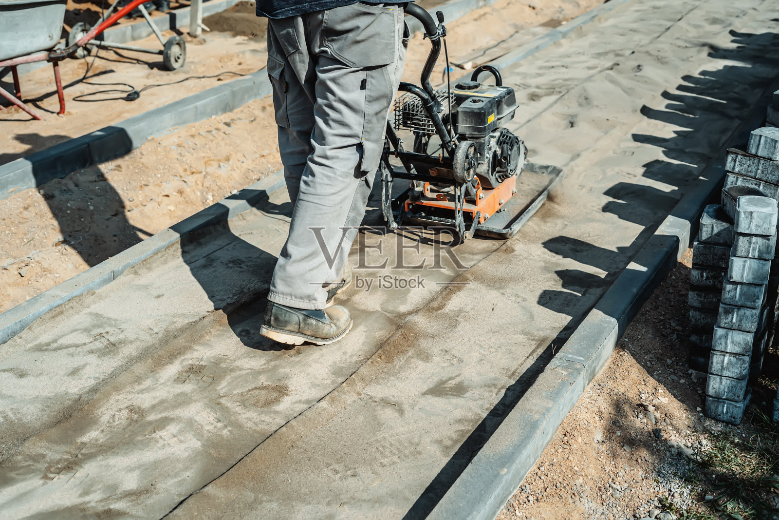 工人用振动机器敲打地面。前视图。照片摄影图片