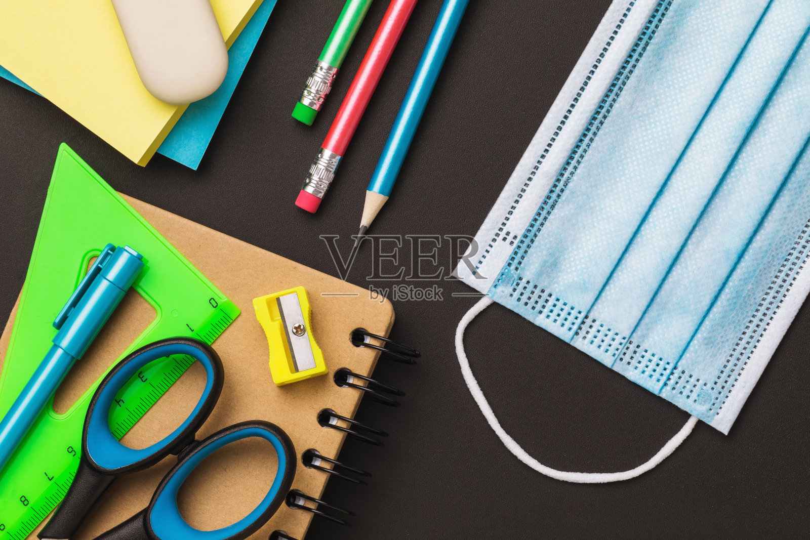 桌上放着学校用品和医用口罩，俯视图。关于在教育机构佩戴口罩问题的概念照片摄影图片