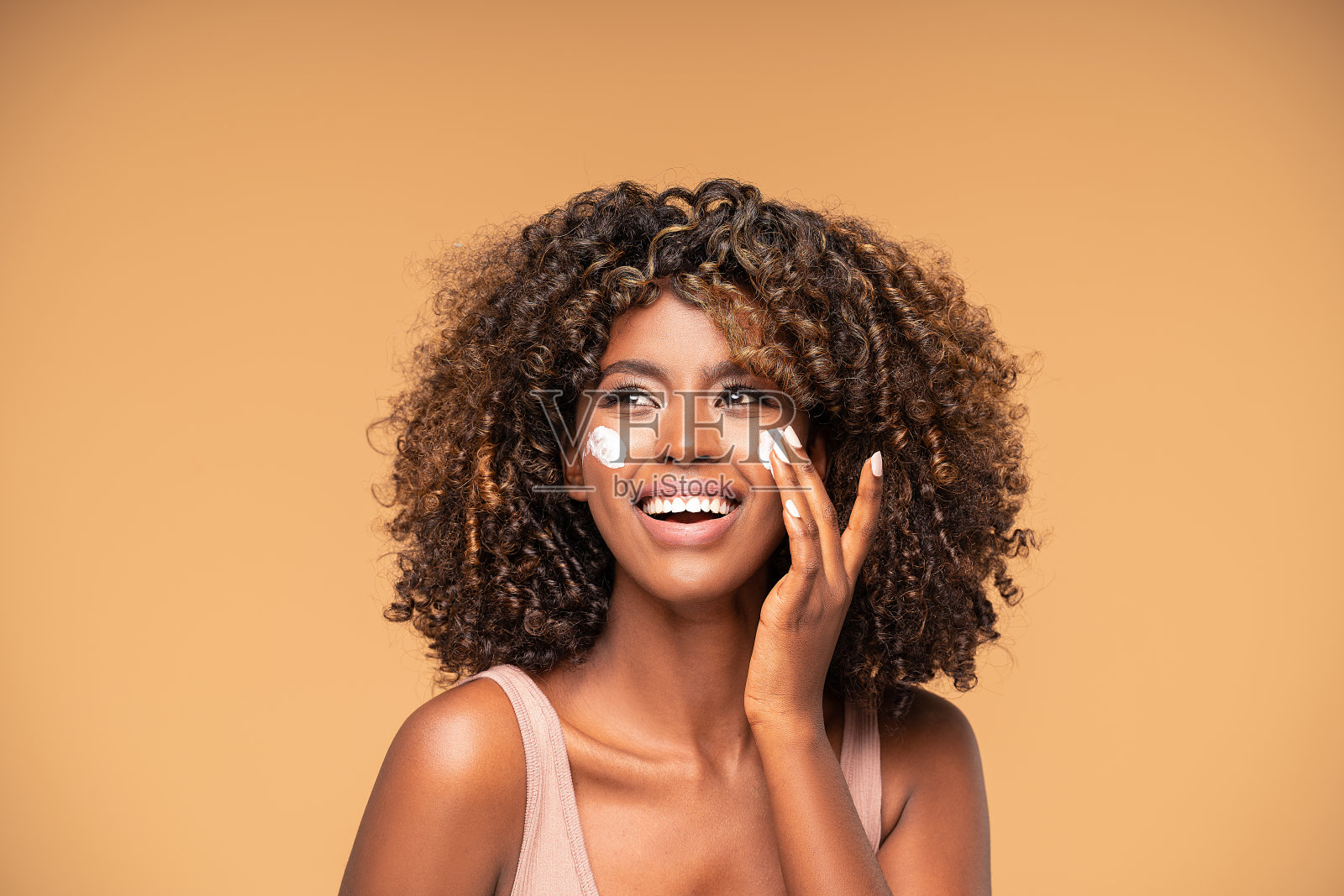 美丽的非洲女孩在脸颊上涂霜。照片摄影图片