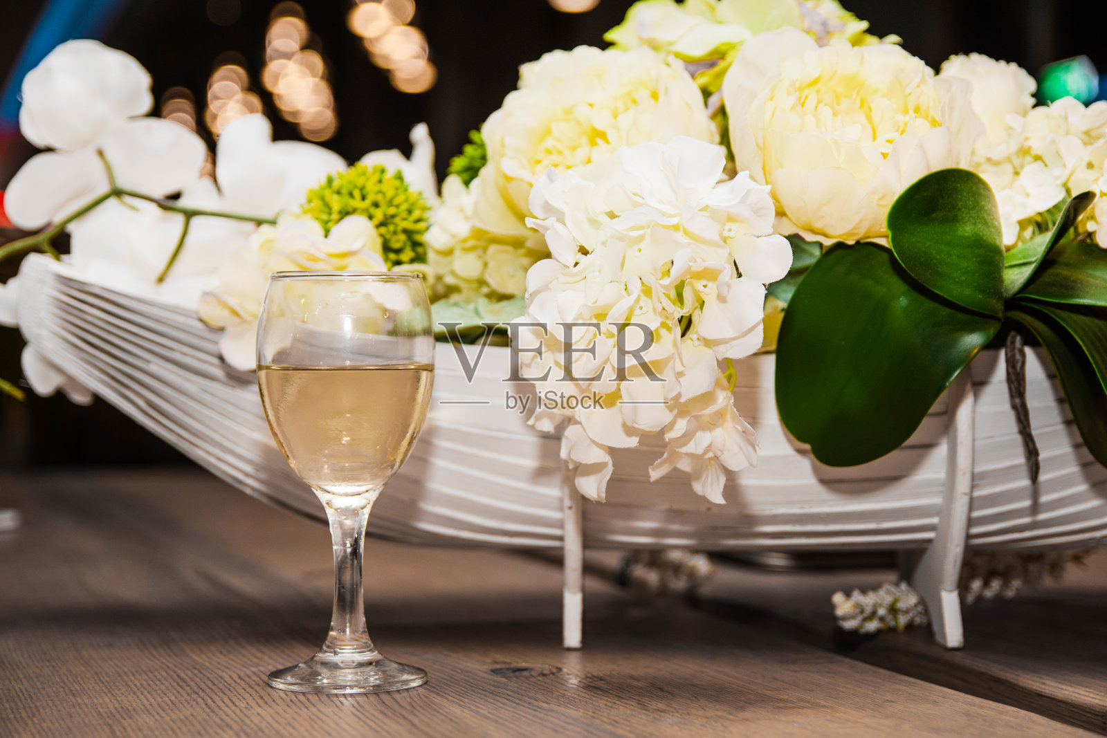一杯白葡萄酒和一束人造花。照片摄影图片