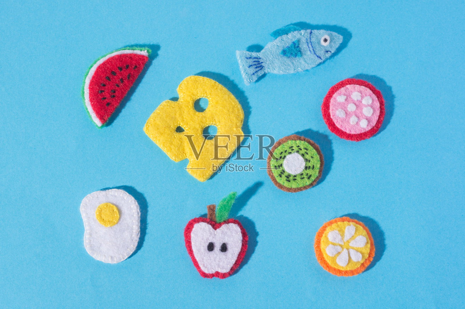 在蓝色背景上用毛毡手工制作的食物和水果玩具。手缝照片摄影图片