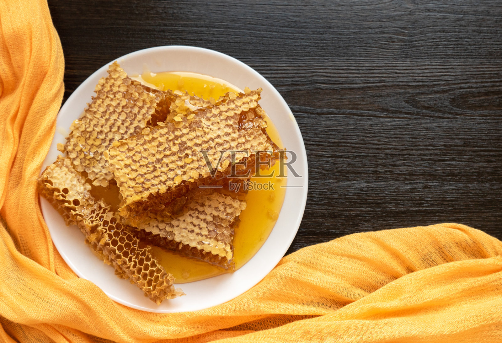 木桌上白色盘子里的蜂巢。天然有机蜂产品。健康的生活方式。为你的文本复制空间。特写照片。照片摄影图片